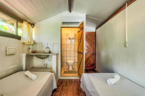 a room with two beds and a bathroom with a sink at Pousada Boas Ondas in Itacaré