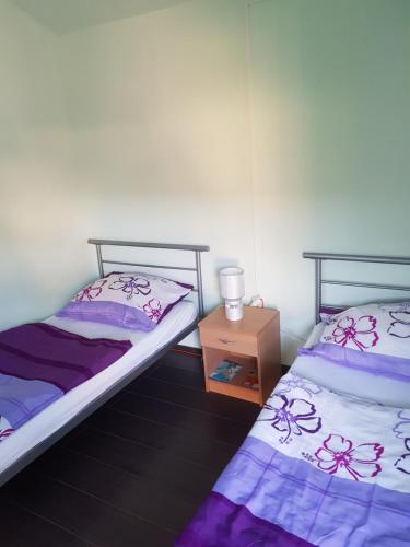 two beds in a room with a night stand at Napraforgó Apartmanok in Balatonfůzfő