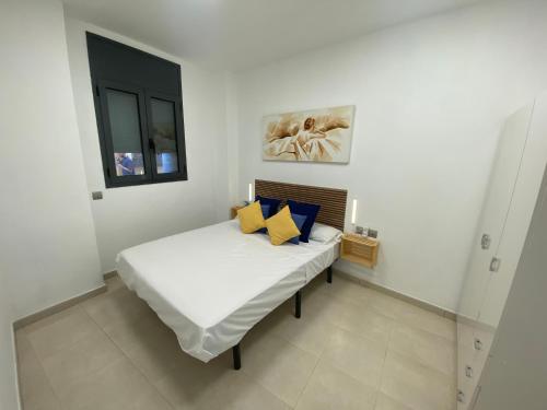 een slaapkamer met een bed met gele en blauwe kussens bij Apartaments Puigcardener BX in Manresa