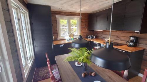 cocina con armarios negros y mesa de madera en Ny tømmerhytte en Tveiten