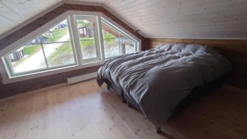 1 dormitorio con 1 cama en una habitación con ventanas en Ny tømmerhytte en Tveiten