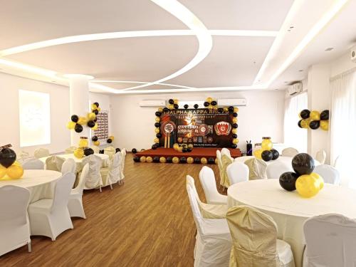 a banquet hall with white tables and chairs and a stage at Majestic Hotel in Manama