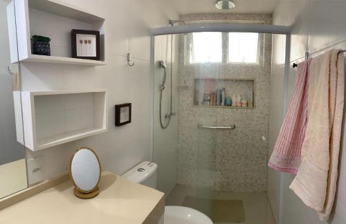 uma casa de banho branca com um chuveiro e um WC. em Refúgio praiano: Apto reformado a 100m da praia no Rio de Janeiro