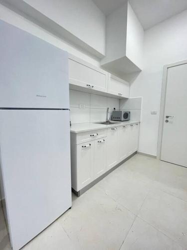 a kitchen with white cabinets and a white refrigerator at Zan in Netanya