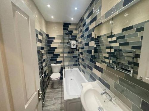 y baño con bañera, aseo y lavamanos. en Charming 5 Bed - Leytonstone E11, en Londres