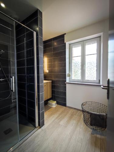 La salle de bains est pourvue d'une douche avec du carrelage noir. dans l'établissement LA HALTE 19, à Ban-sur-Meurthe-Clefcy