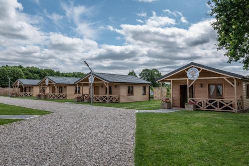 a row of wooden lodges on a gravel road at Osada Trzy Siostry in Pobierowo