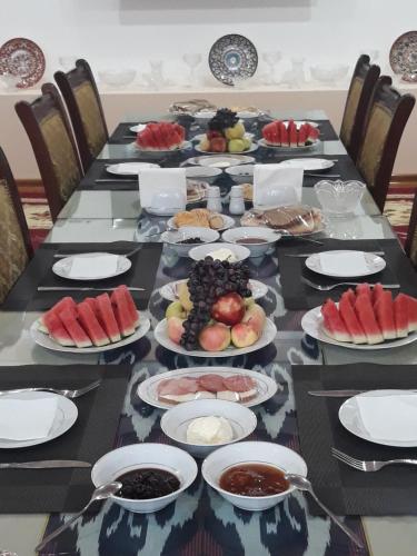 a long table with plates of food and fruit at Guest House Orzu in Khiva
