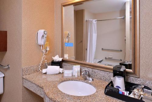 a bathroom with a sink with a phone and a mirror at Hampton Inn Jackson-College Avenue in Jackson