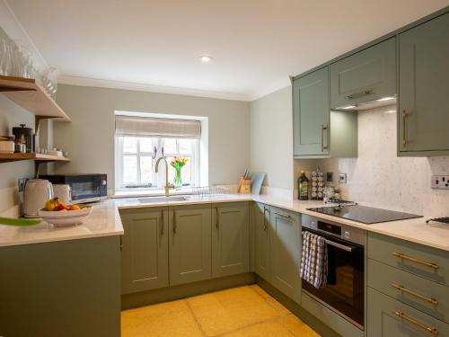 uma cozinha com armários verdes e uma janela em The Roost at Coln em Coln Saint Aldwyn