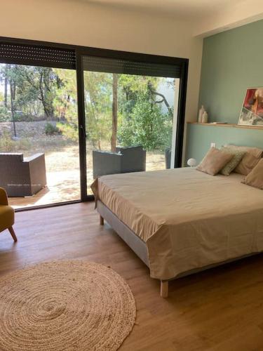 une chambre avec un grand lit et une grande fenêtre dans l'établissement Maison proche du pic Saint Loup, à Saint-Jean-de-Cuculles