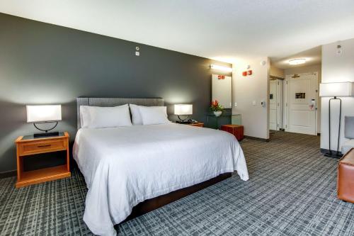 um quarto de hotel com uma cama grande com lençóis brancos em Hilton Garden Inn Louisville Airport em Louisville