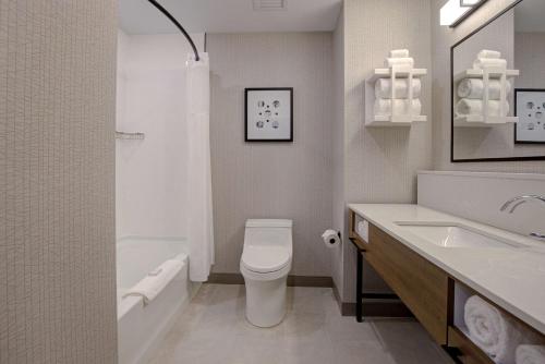 a white bathroom with a toilet and a sink at Homewood Suites By Hilton Montreal Downtown in Montréal