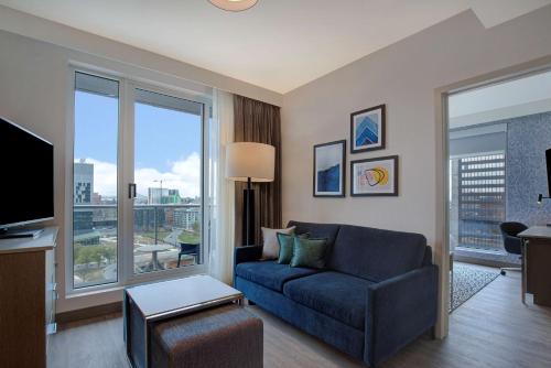 a living room with a couch and a large window at Homewood Suites By Hilton Montreal Downtown in Montreal