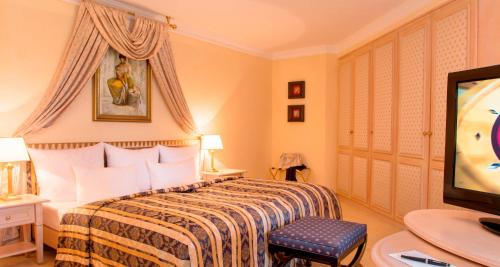 a hotel room with a bed and a flat screen tv at Victor's Residenz-Hotel Schloss Berg in Nennig
