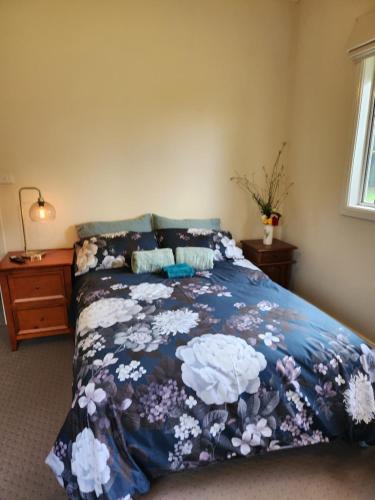 Una cama con un edredón azul con flores. en Ashmore Park en Armidale