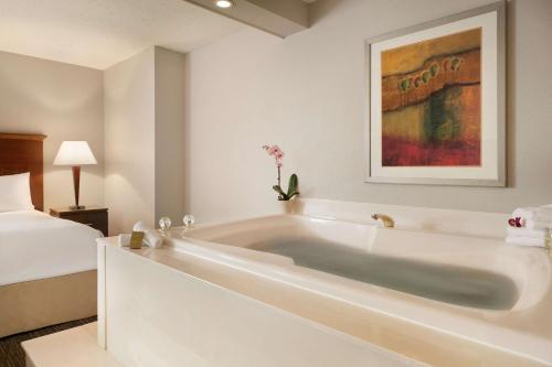 a white bath tub in a room with a bed at DoubleTree by Hilton Minneapolis Park Place in Saint Louis Park