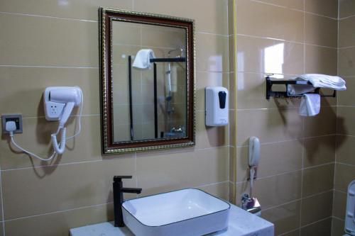 ein Bad mit einem Spiegel, einem Waschbecken und einem Telefon in der Unterkunft Dellagio Hotel in Wa