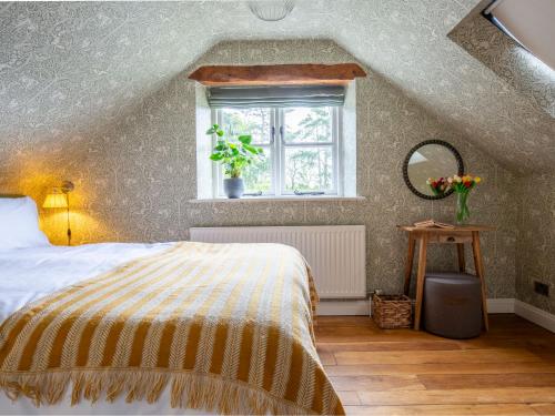 a bedroom with a bed and a window at The Roost at Coln in Coln Saint Aldwyn