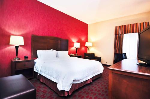 um quarto de hotel com uma cama grande e paredes vermelhas em Hampton Inn Carrollton KY em Carrollton