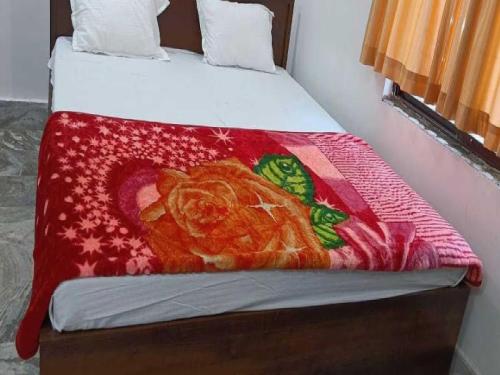 a bed with a red blanket with a cat on it at OYO Hotel K2 in Bihta