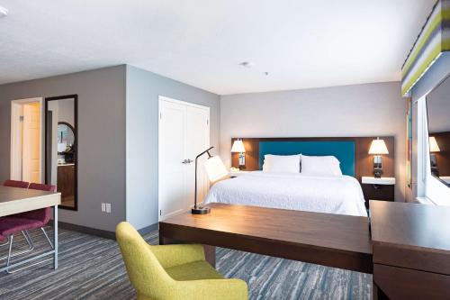 a hotel room with a bed and a desk and chairs at Hampton Inn & Suites Salt Lake City Airport in Salt Lake City