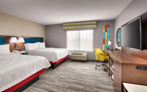 a hotel room with two beds and a flat screen tv at Hampton Inn & Suites Salt Lake City Airport in Salt Lake City