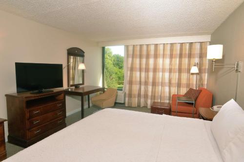 Habitación de hotel con cama, escritorio y TV. en Hampton Inn Springfield-South, en Springfield