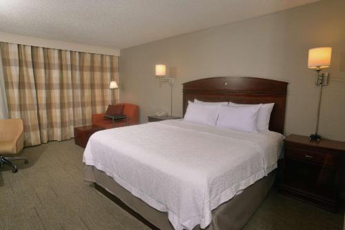 スプリングフィールドにあるHampton Inn Springfield-Southの大きなベッドと椅子が備わるホテルルームです。