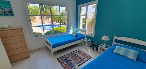 1 dormitorio azul con 2 camas y piscina en Villa Laonari, en Tsadha