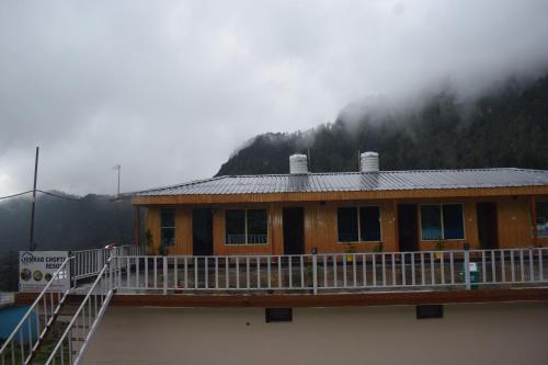 a building with a snow covered roof with a misty mountain at Himrab Chopta Resort in Chopta