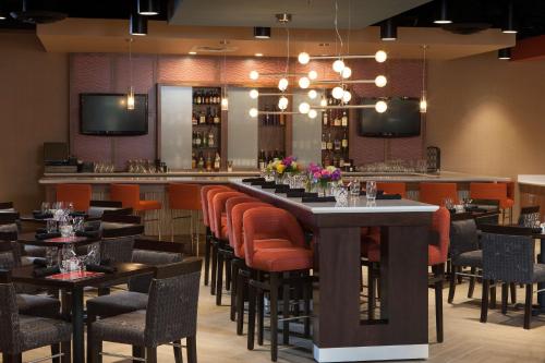 a restaurant with a long bar with orange chairs at DoubleTree by Hilton Murfreesboro in Murfreesboro