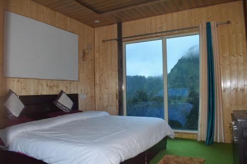 a bedroom with a bed and a large window at Himrab Chopta Resort in Chopta