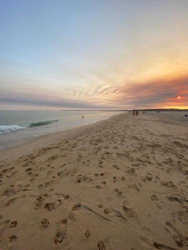 a beach with footprints in the sand at sunset at Clube Alvor Ria in Alvor