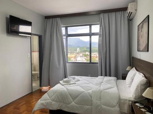 a bedroom with a large bed and a large window at Hotel Embaixador in Cruzeiro