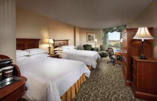 una camera d'albergo con tre letti e una finestra di DoubleTree by Hilton Lisle Naperville a Lisle