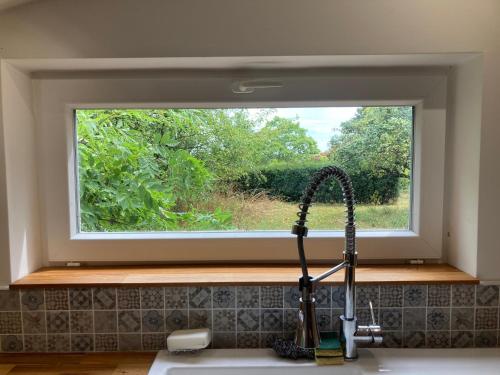 eine Küchenspüle mit einem Fenster über einer Küchentheke in der Unterkunft Maison de charme in Thil-sur-Arroux