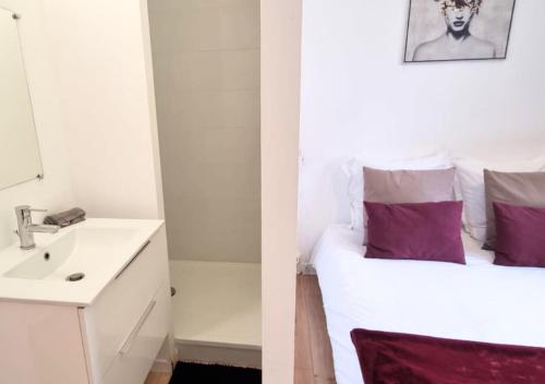 La salle de bains est pourvue d'un lavabo et d'un lit avec des oreillers violets. dans l'établissement 