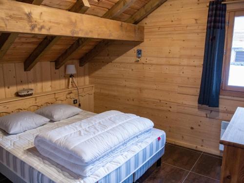 uma cama grande num quarto com paredes de madeira em L'Ecrin des Granges - La Cime em Villarembert