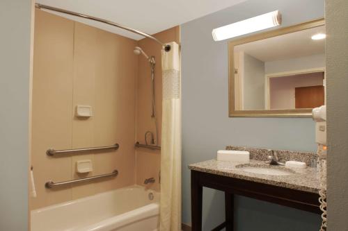 uma casa de banho com um lavatório, uma banheira e um espelho. em Hampton Inn & Suites Port St. Lucie em Port Saint Lucie