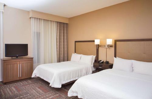 a hotel room with two beds and a flat screen tv at Hampton Inn & Suites Valdosta/Conference Center in Valdosta