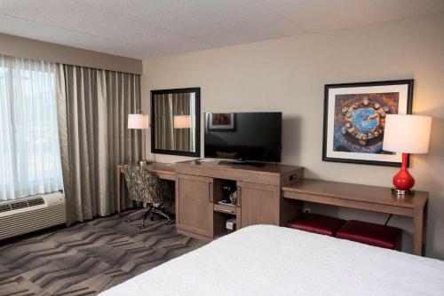 a hotel room with a bed and a desk with a television at Hampton Inn & Suites by Hilton Thunder Bay in Thunder Bay