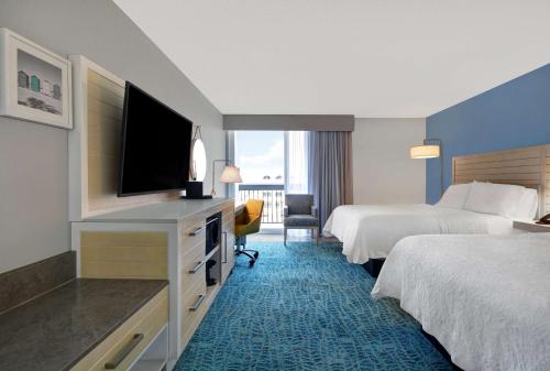 a hotel room with two beds and a flat screen tv at Hampton Inn Oceanfront Jacksonville Beach in Jacksonville Beach