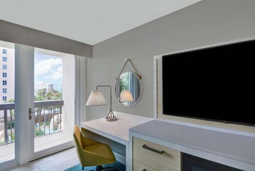 a living room with a large television and a chair at Hampton Inn Oceanfront Jacksonville Beach in Jacksonville Beach