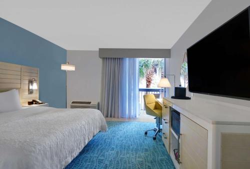 a hotel room with a bed and a flat screen tv at Hampton Inn Oceanfront Jacksonville Beach in Jacksonville Beach