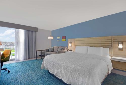 a hotel room with a large bed and a chair at Hampton Inn Oceanfront Jacksonville Beach in Jacksonville Beach