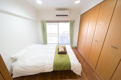 1 dormitorio con cama blanca y ventana en Shibuya E Address 303, en Tokio