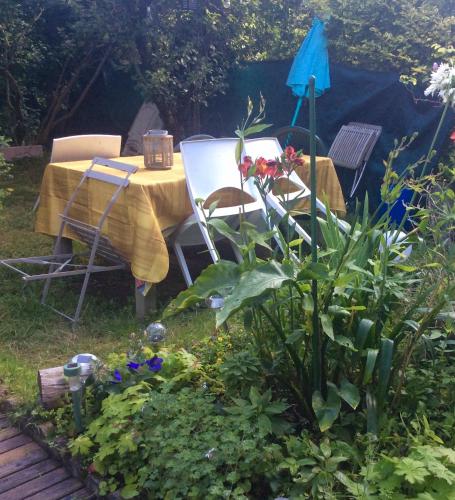 une table et des chaises dans un jardin fleuri dans l'établissement Maison Lorient Sud, à Lorient