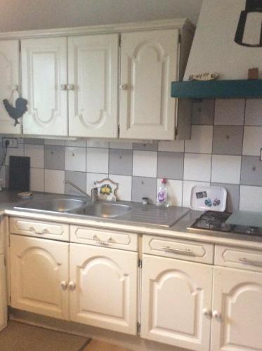 une cuisine avec des armoires blanches et un évier dans l'établissement Maison Lorient Sud, à Lorient