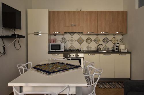 a kitchen with a white table with chairs and a stove at essegiHome in Porto Empedocle